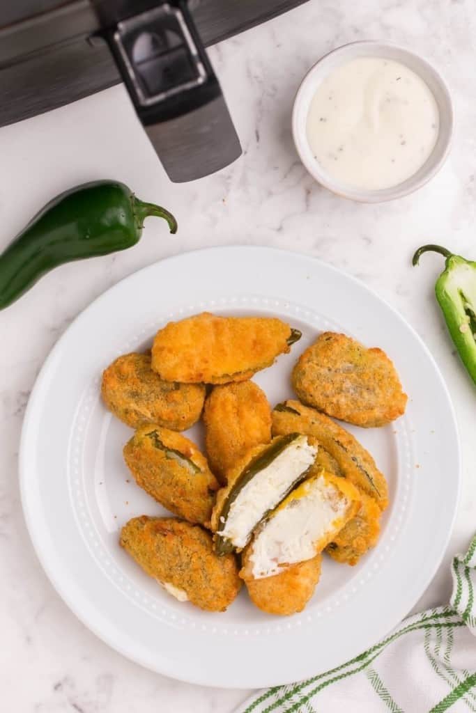 jalapeno poppers on white plate with dipping sauce on side