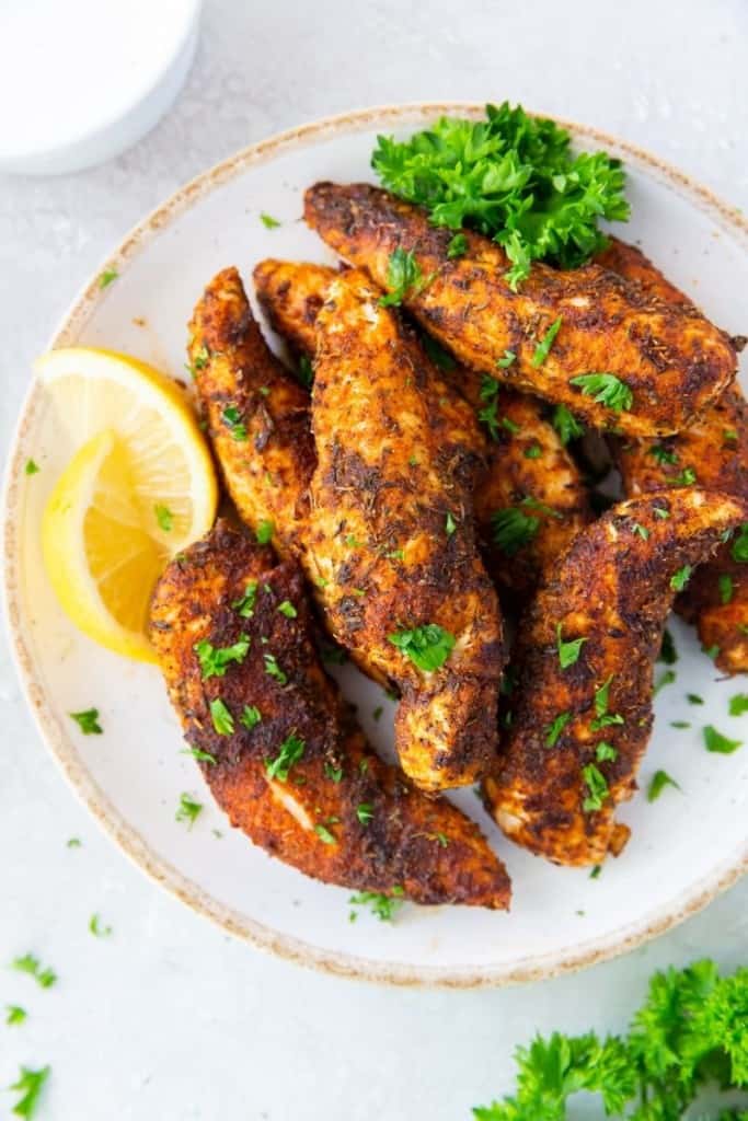 air fryer chicken tenders with no breading on plate with lemon wedges