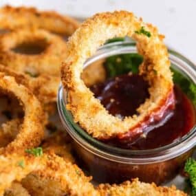 Crispy homemade air fryer onion rings on plate in dipping sauce