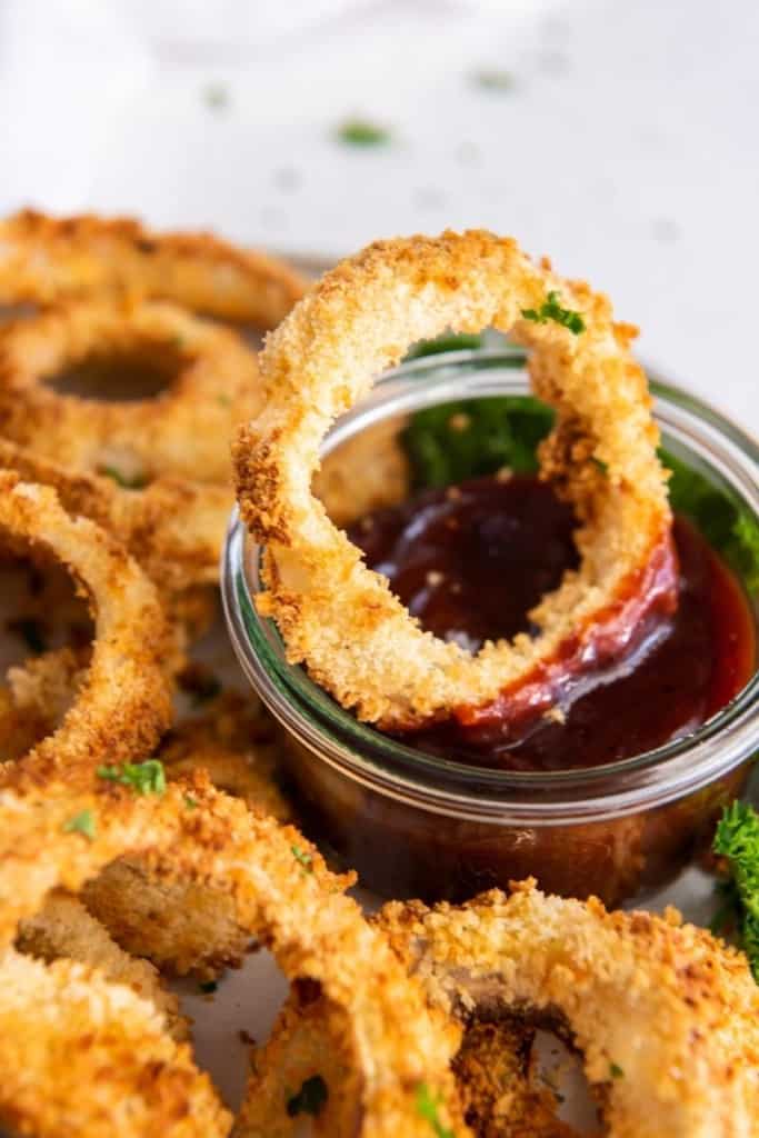 Crispy homemade air fryer onion rings on plate in dipping sauce