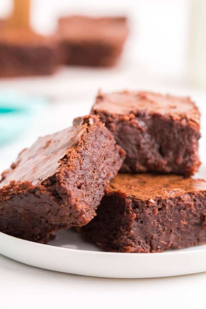 Three fudgy brownies without cocoa powder on plate