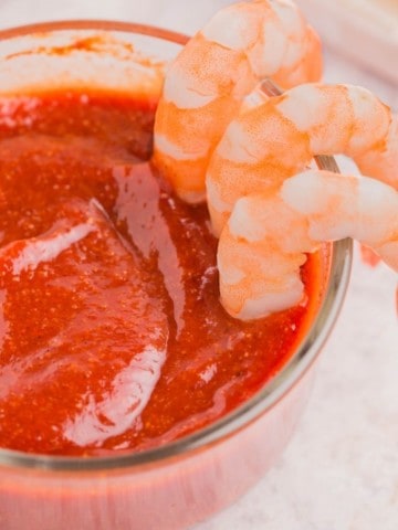 Cocktail sauce without horseradish in dish with shrimp being dipped in