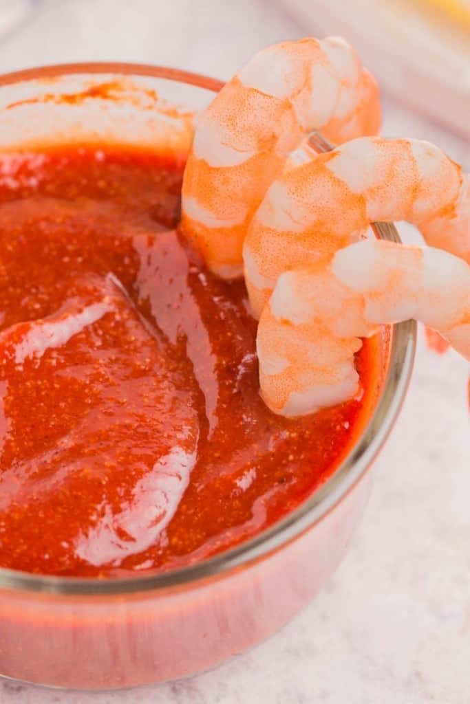 Cocktail sauce without horseradish in dish with shrimp being dipped in