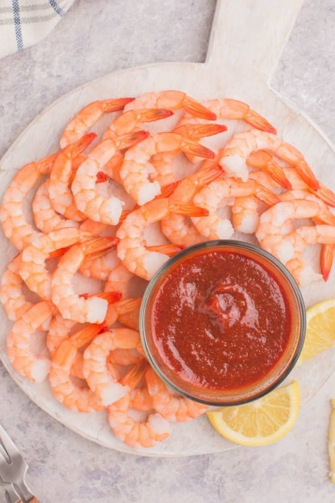full shrimp platter with cocktail sauce and lemon slices on the side