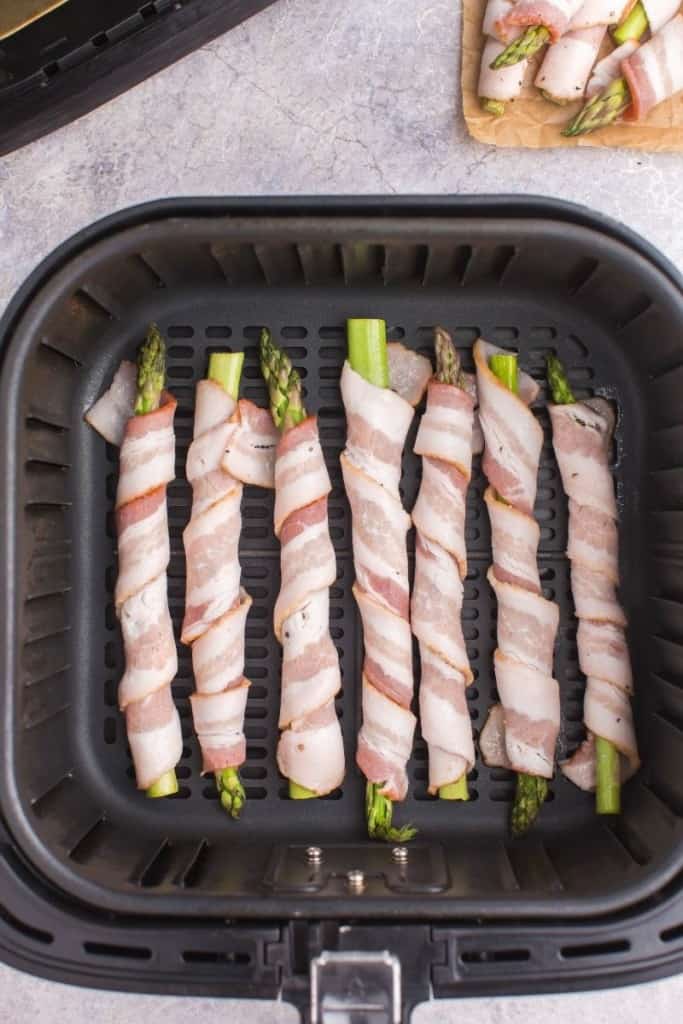place bacon-wrapped asparagus in air fryer to cook