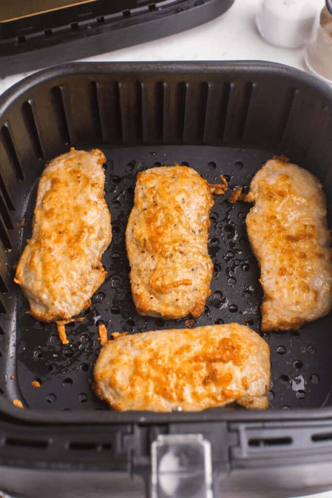 air fryer boneless pork chops inside air fryer with parmesan breading, cooked