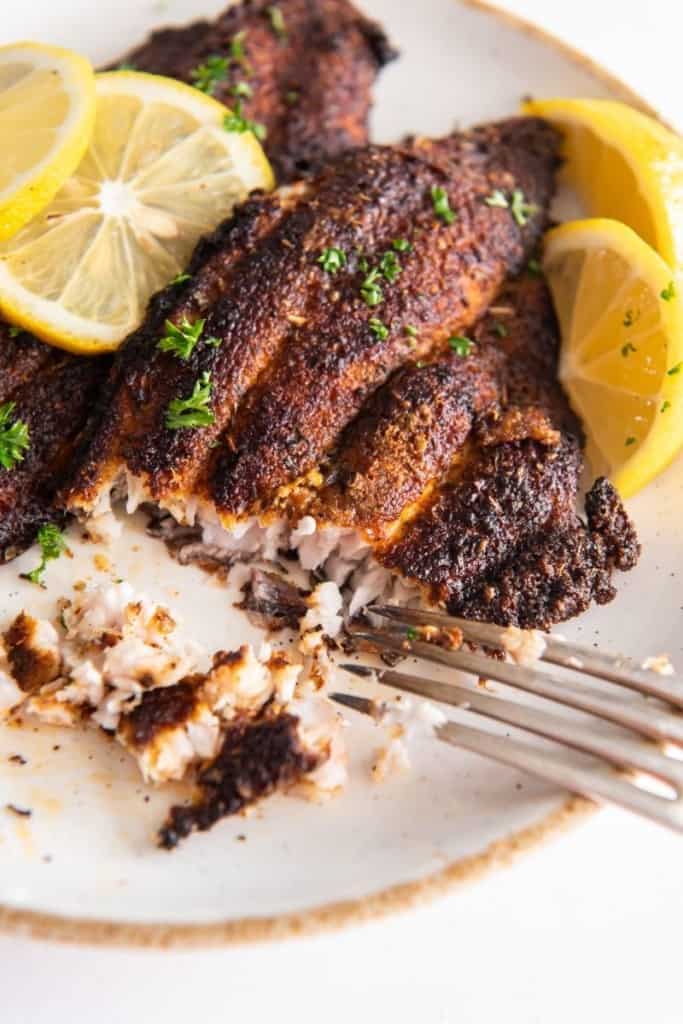 Crispy and tender catfish being cut and eaten with fork