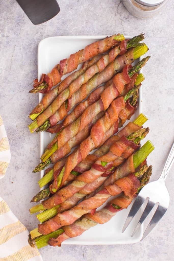 platter with several stalks of asparagus wrapped in bacon cooked in air fryer