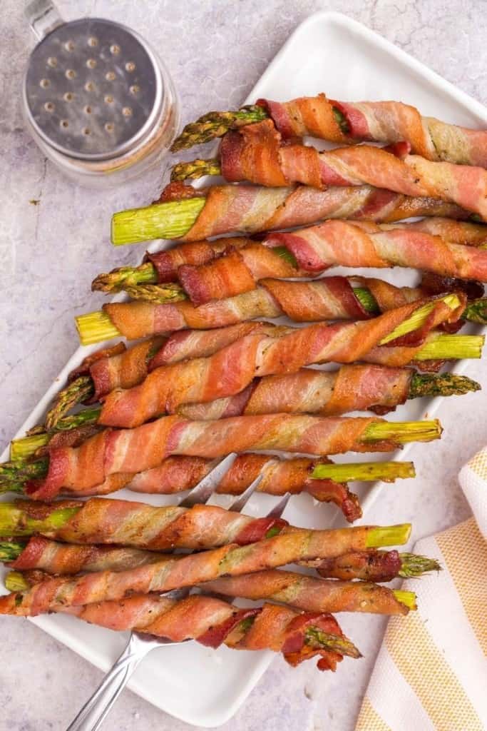 bacon-wrapped asparagus in air fryer on serving platter