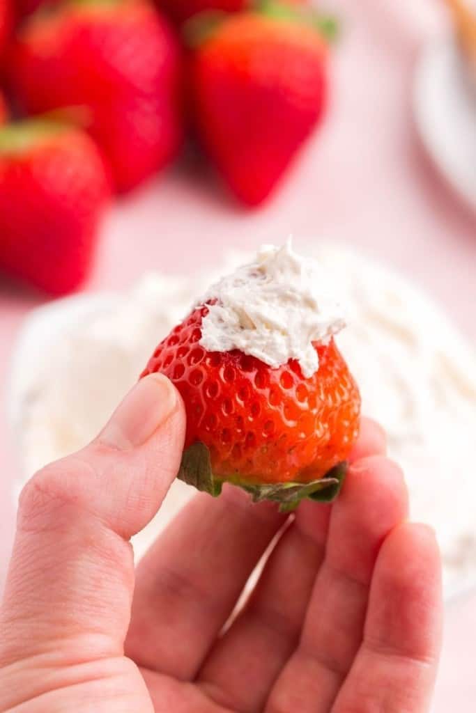 hand holding a strawberry that was dipped in cool whip fruit dip