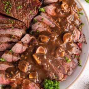London broil cooked in instant pot on plate in slices with sauce