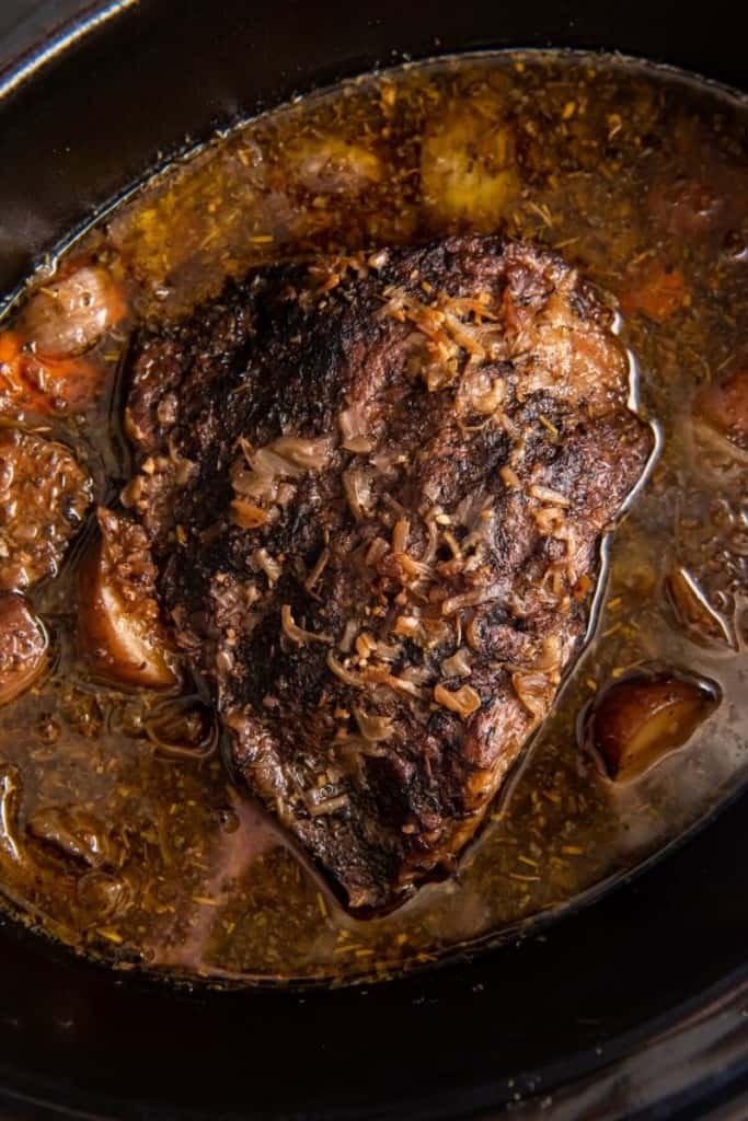 pour broth into crock pot with seasoned vegetables and tri tip roast