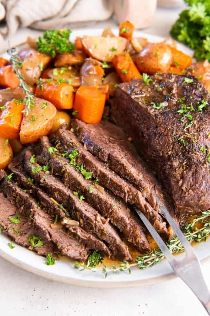 slices of slow cooker tri tip on plate with vegetables