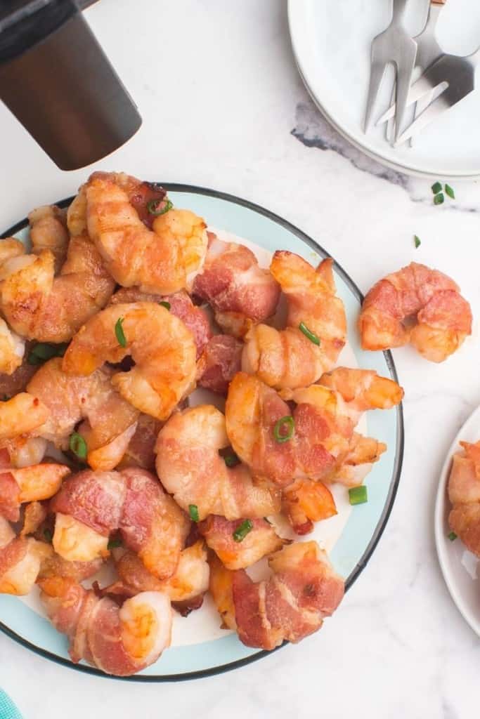 plate with pile of bacon-wrapped shrimp in air fryer