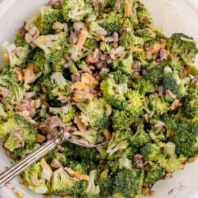 Fresh broccoli salad tossed together in bowl with fork