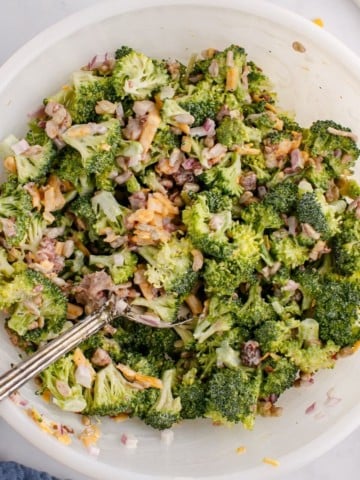 Fresh broccoli salad tossed together in bowl with fork
