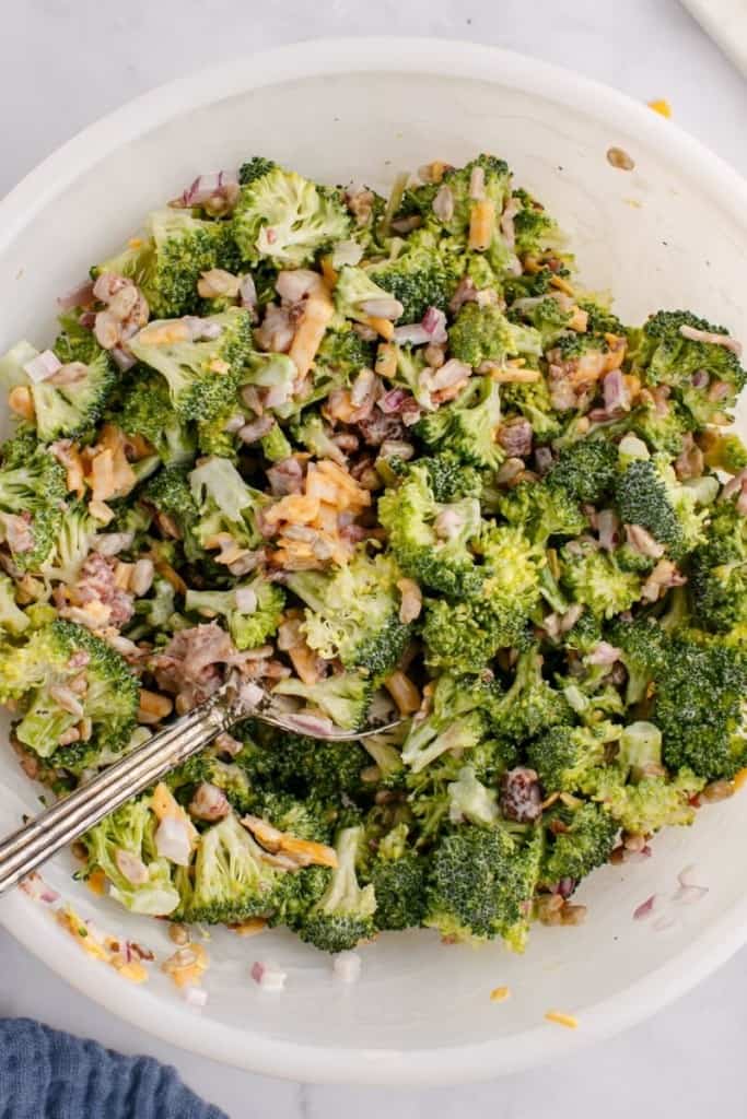 Fresh broccoli salad tossed together in bowl with fork