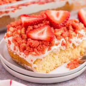A piece of strawberry shortcake crumble on a plate with sliced strawberries on top