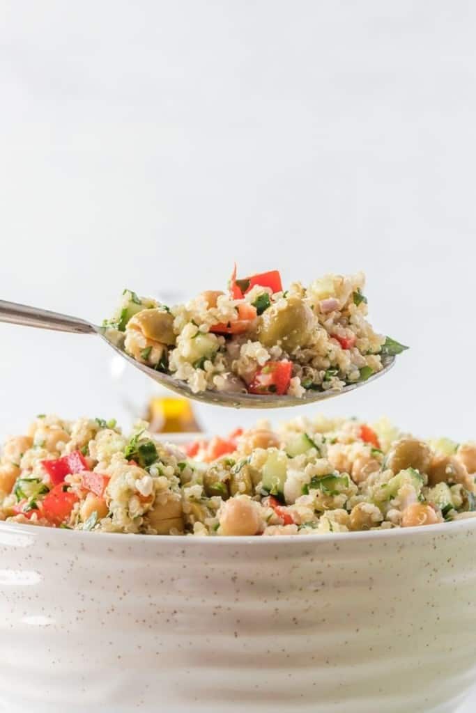 Spoon lifting bite of quinoa chickpea salad out of bowl