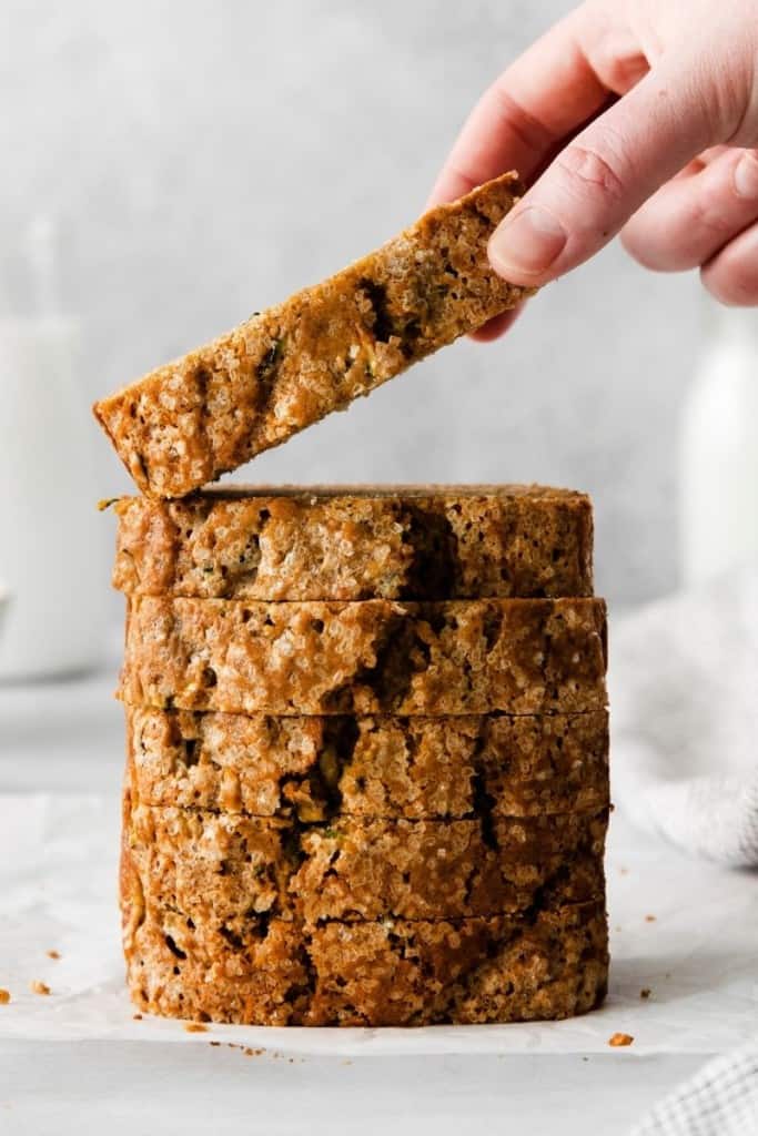 Someone taking slice of zucchini bread from a stack