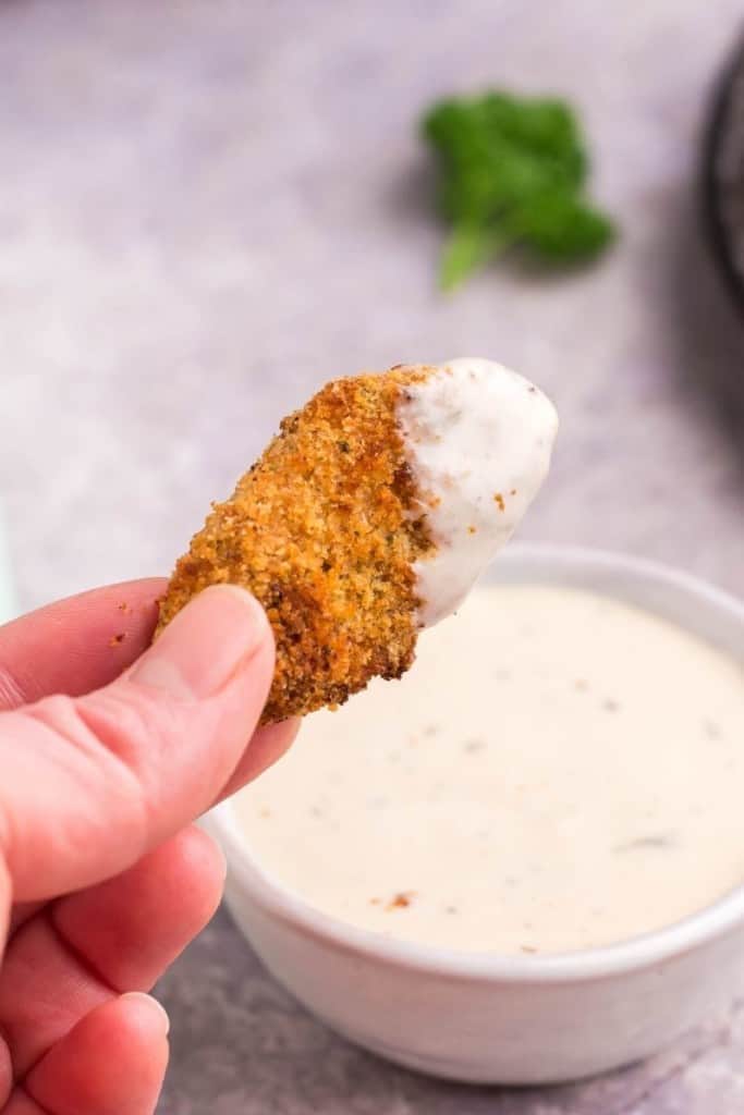 hand dipping air fryer chicken nugget into ranch