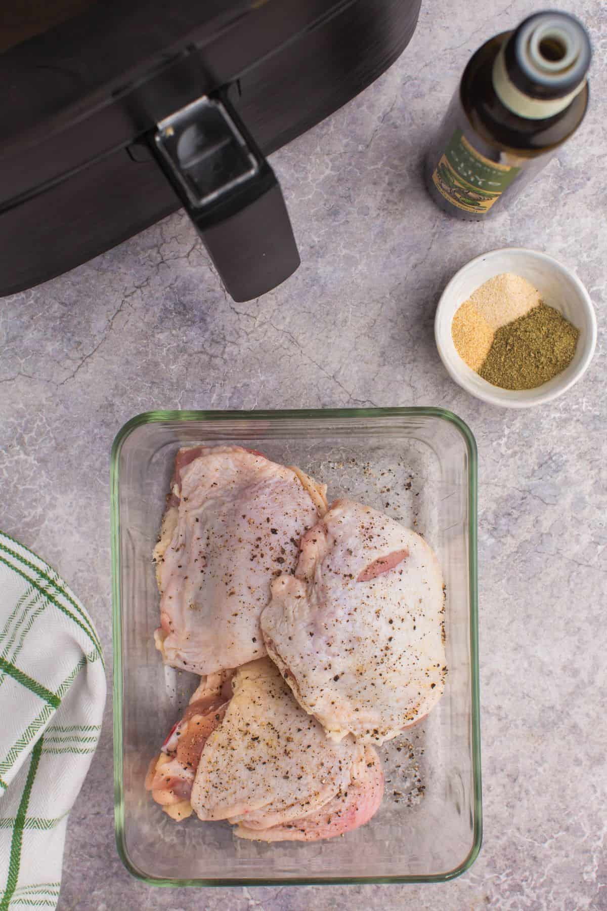Ingredients needed to make bone in chicken thighs in the air fryer: chicken thighs, oil, salt, pepper, garlic powder, onion powder, and poultry seasoning.