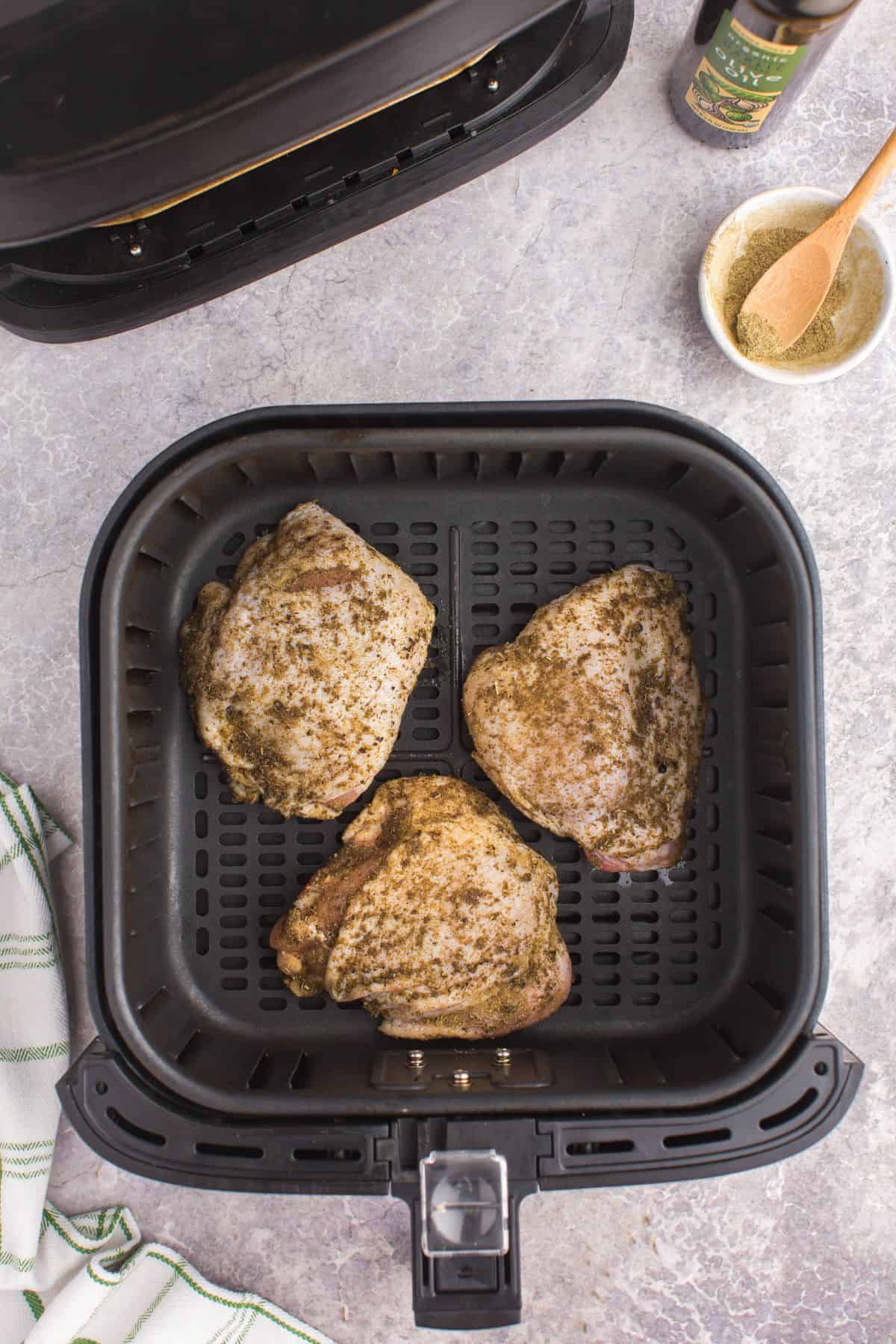 Raw chicken thighs in the air fryer about to be cooked.