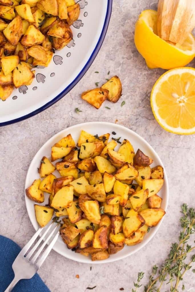 air fryer diced potatoes in bowl with lemon halves