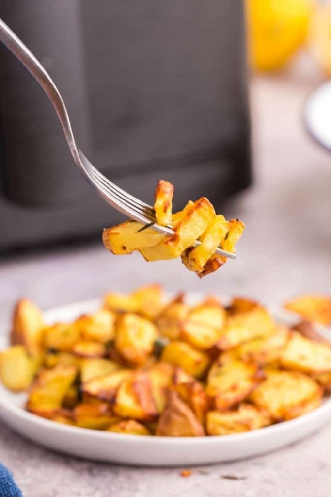 Fork dishing up fresh diced potatoes cooked in air fryer