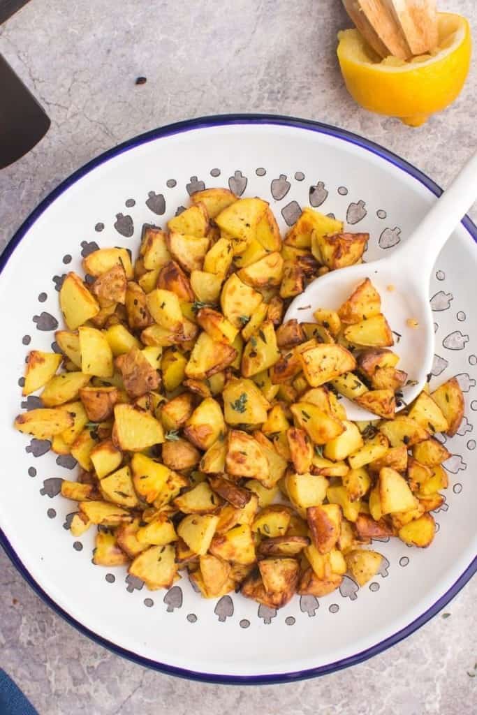 diced potatoes cooked in air fryer in bowl with spoon