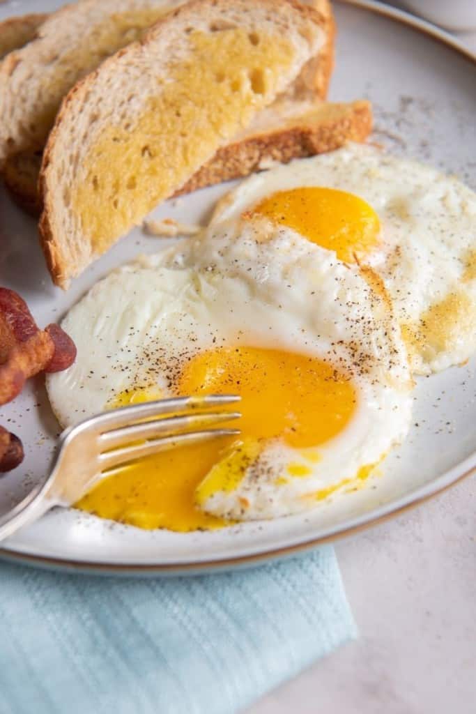 Fork cutting into runny yolk of an air fryer fried egg