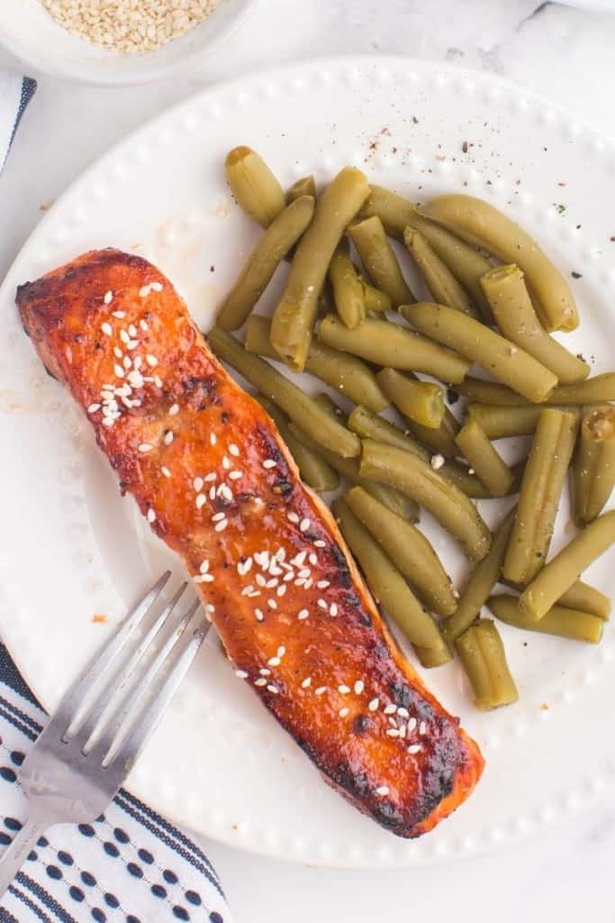 white plate with air fryer teriyaki salmon and green beans
