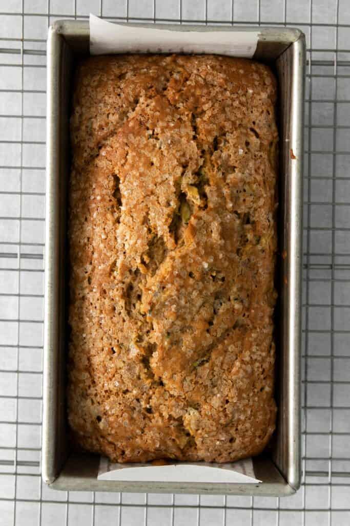 Cooked loaf of easy zucchini bread still in the bread pan on a wire rack.