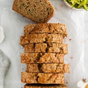 Zucchini bread with applesauce sliced on a counter with a piece lying flat to see the inside.