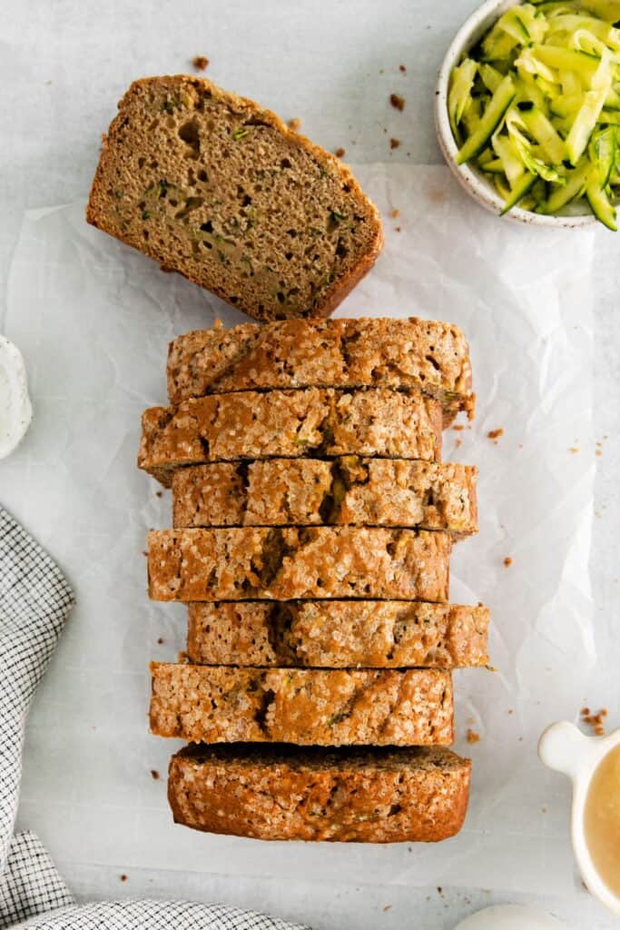 Zucchini bread with applesauce sliced on a counter with a piece lying flat to see the inside.