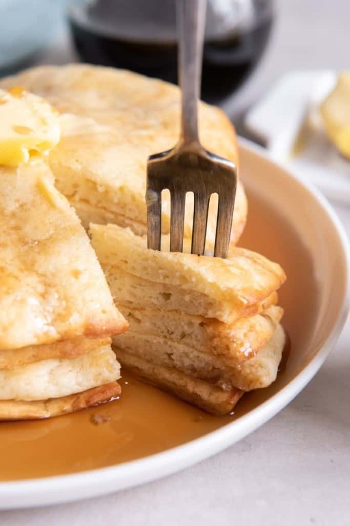 Fork lifting slices of several air fryer pancakes