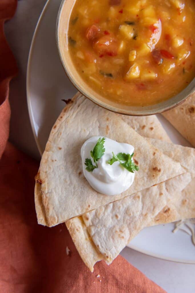 Overhead view of cut up air fryer quesadilla pieces with a dollop of sour cream on top.