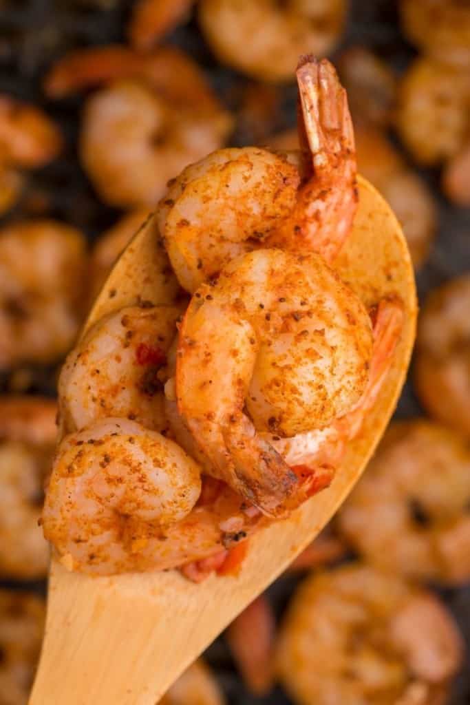 close up of cooked shrimp on wooden spoon