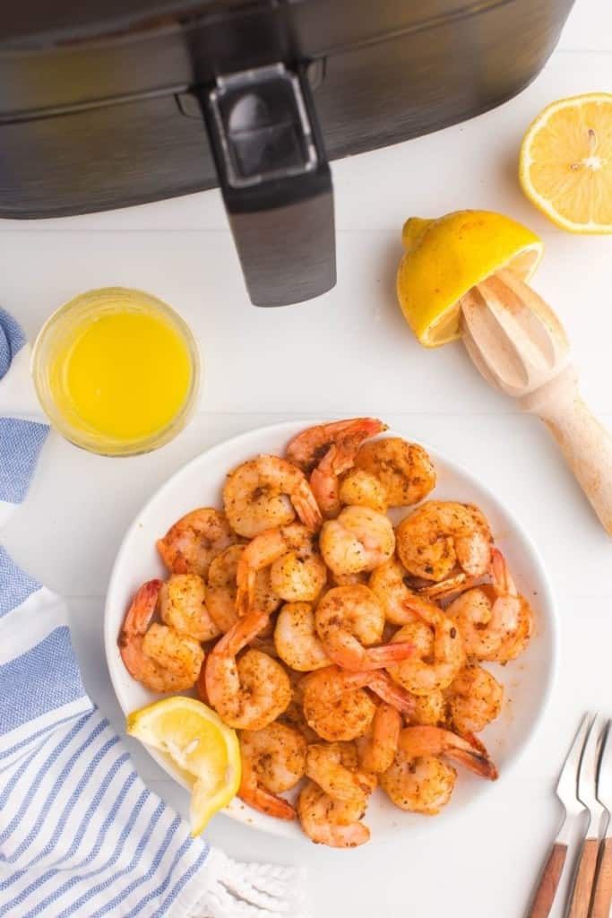cooked shrimp in bowl with lemon wedges and sauce on the side