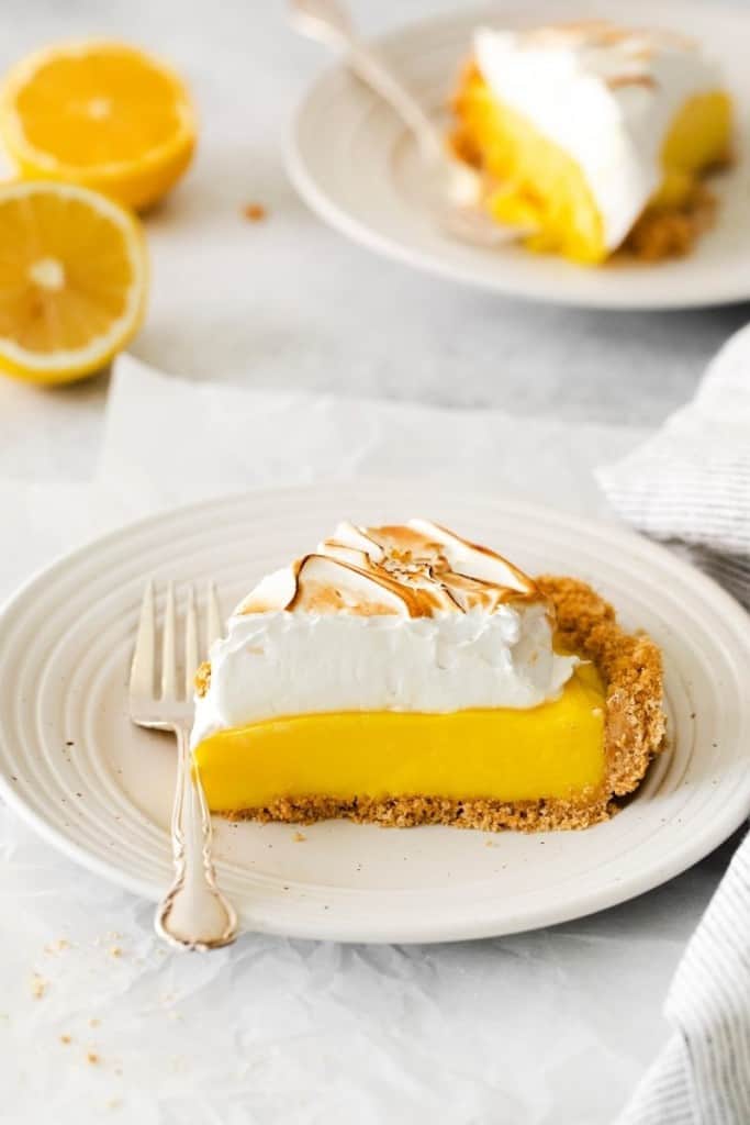 Piece of lemon meringue pie on plate with a bite taken out