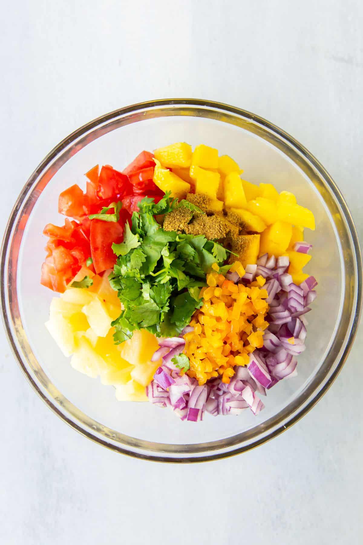 All mango salsa recipe ingredients added to a bowl.