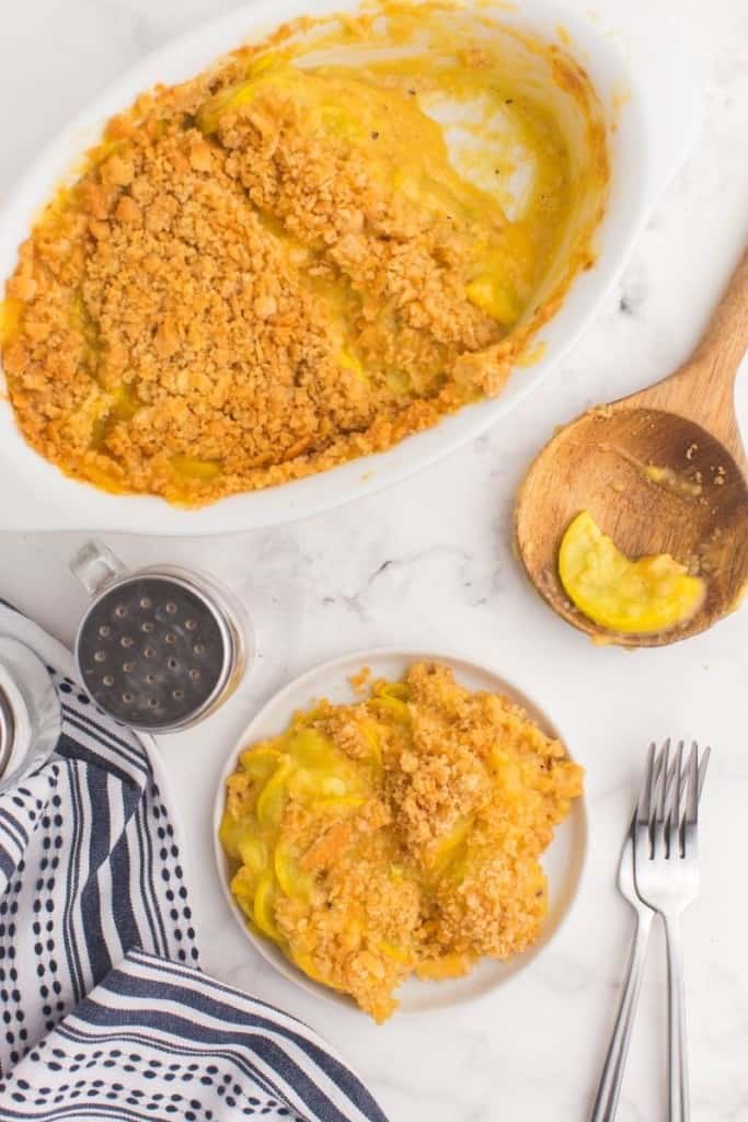 plate full of squash casserole with fork next to casserole dish