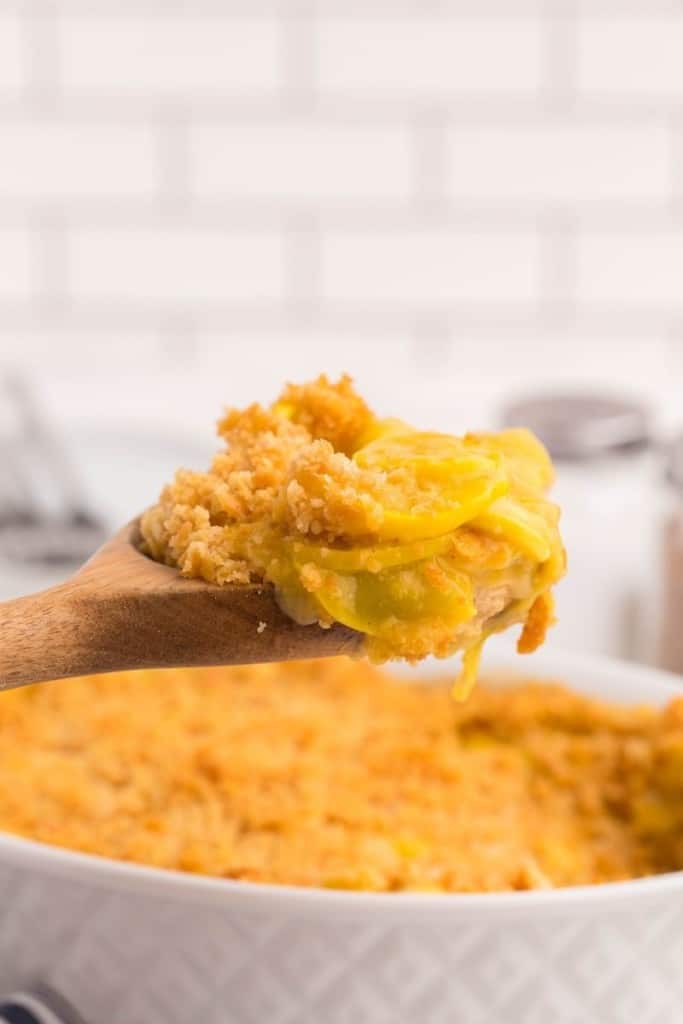 Spatula dishing up some cheesy yellow squash casserole