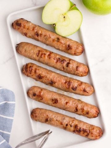 air fryer chicken sausages lined up on white plate