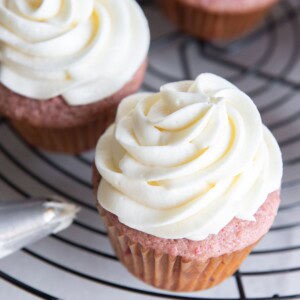 Cream cheese frosting piped on top of strawberry cupcakes.