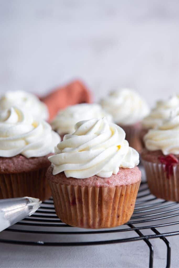 Side view of the cream cheese frosting without butter piped on strawberry cupcakes.