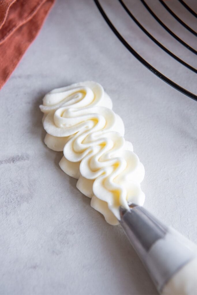 Cream cheese frosting without butter piped out in a wavy pattern on the counter.