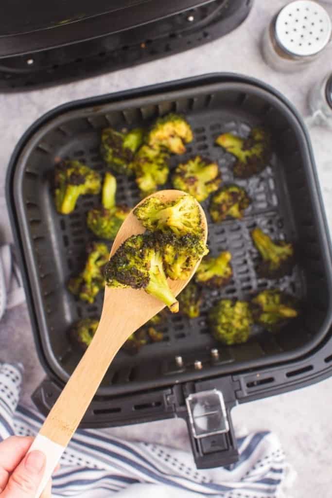 wooden spoon dishing broccoli out of air fryer