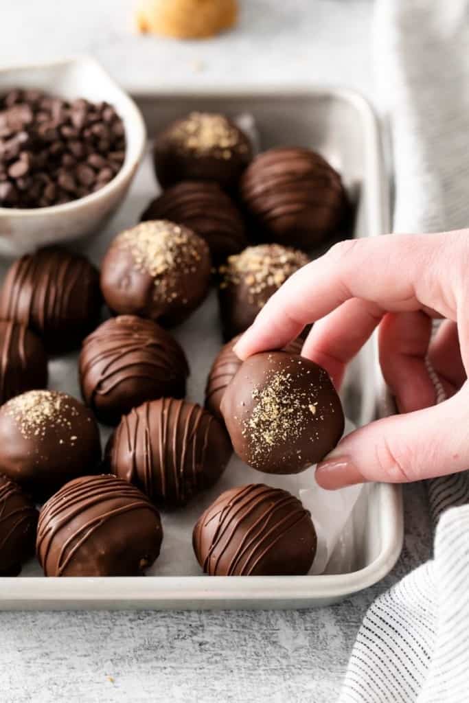 peanut butter balls on tray with hand grabbing one