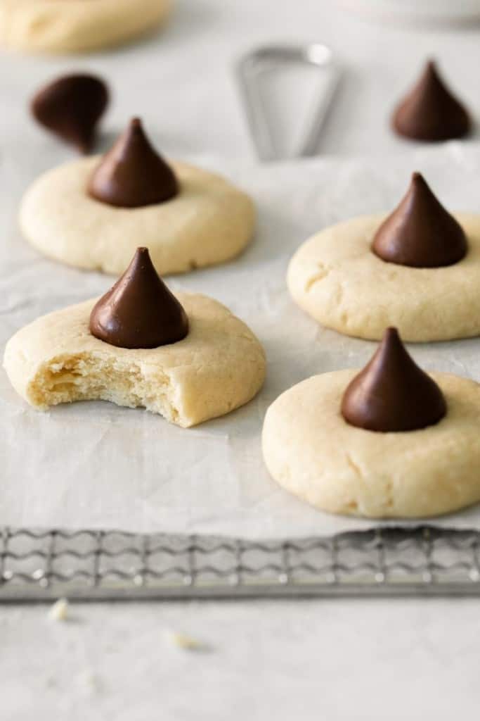 Several sugar cookies topped with hershey kisses on parchment paper